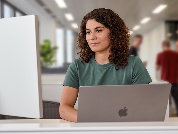 Una persona del team Apple che usa un MacBook e uno Studio Display in un ufficio.