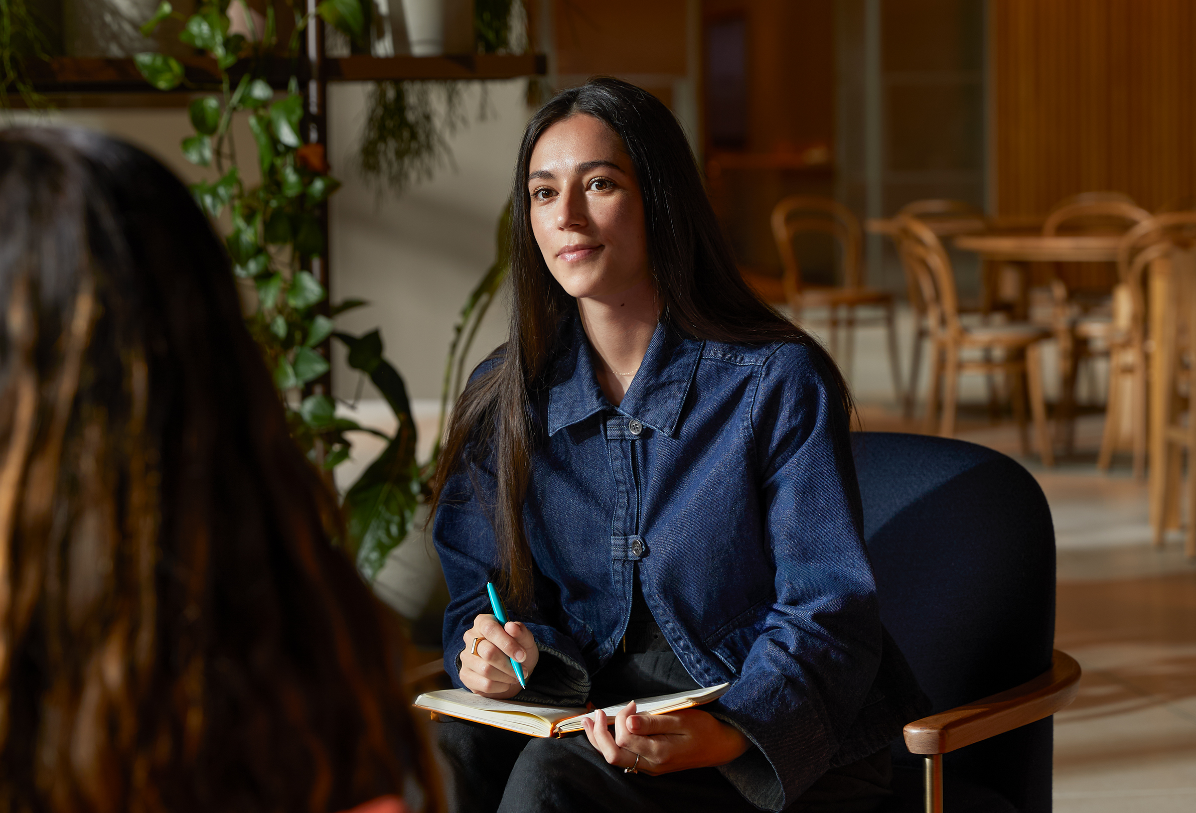 Una persona del team Apple seduta a un tavolo di uno spazio comune mentre parla con una collega.