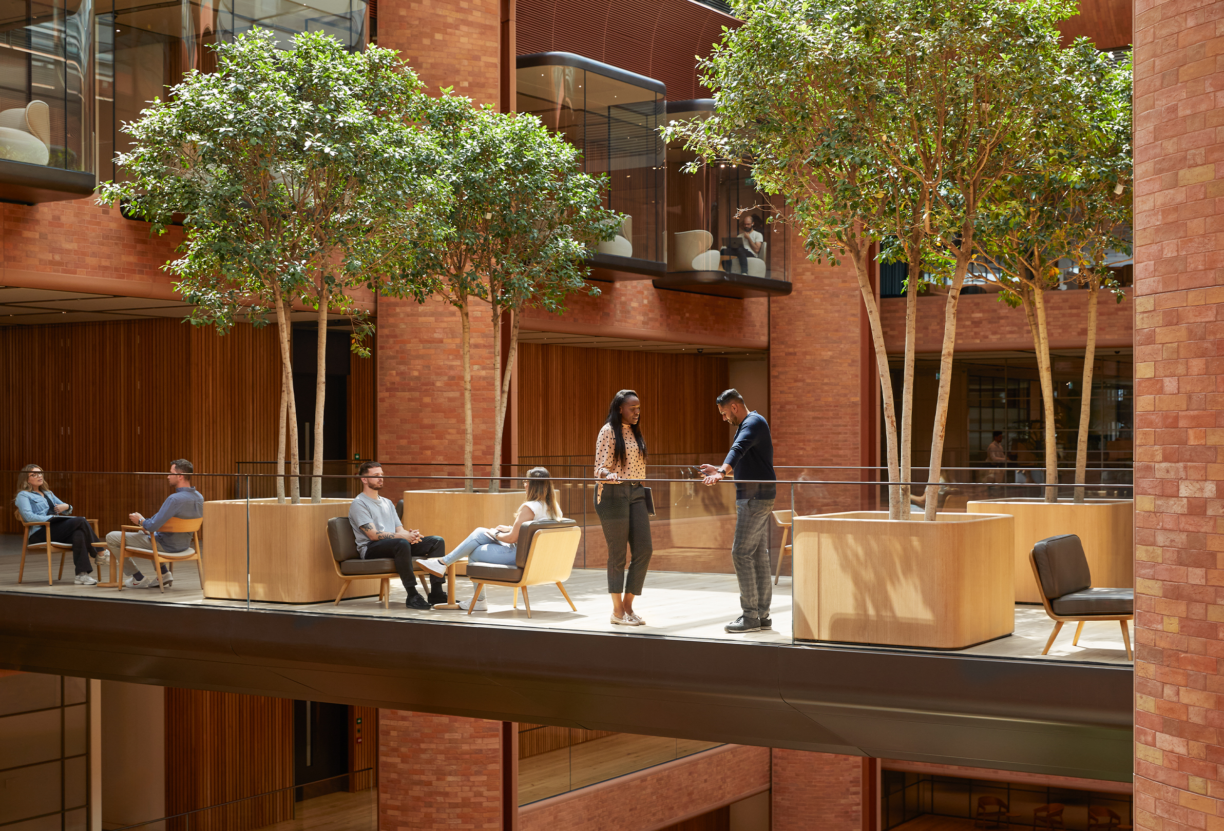 Alcune persone del team Apple impegnate in varie conversazioni nell’atrio del campus di Battersea.