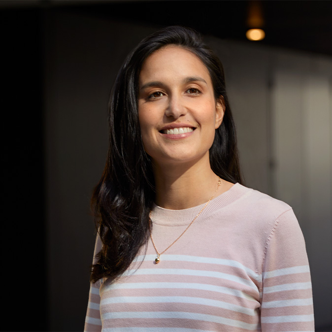 Camila standing indoors, smiling, in an office space.