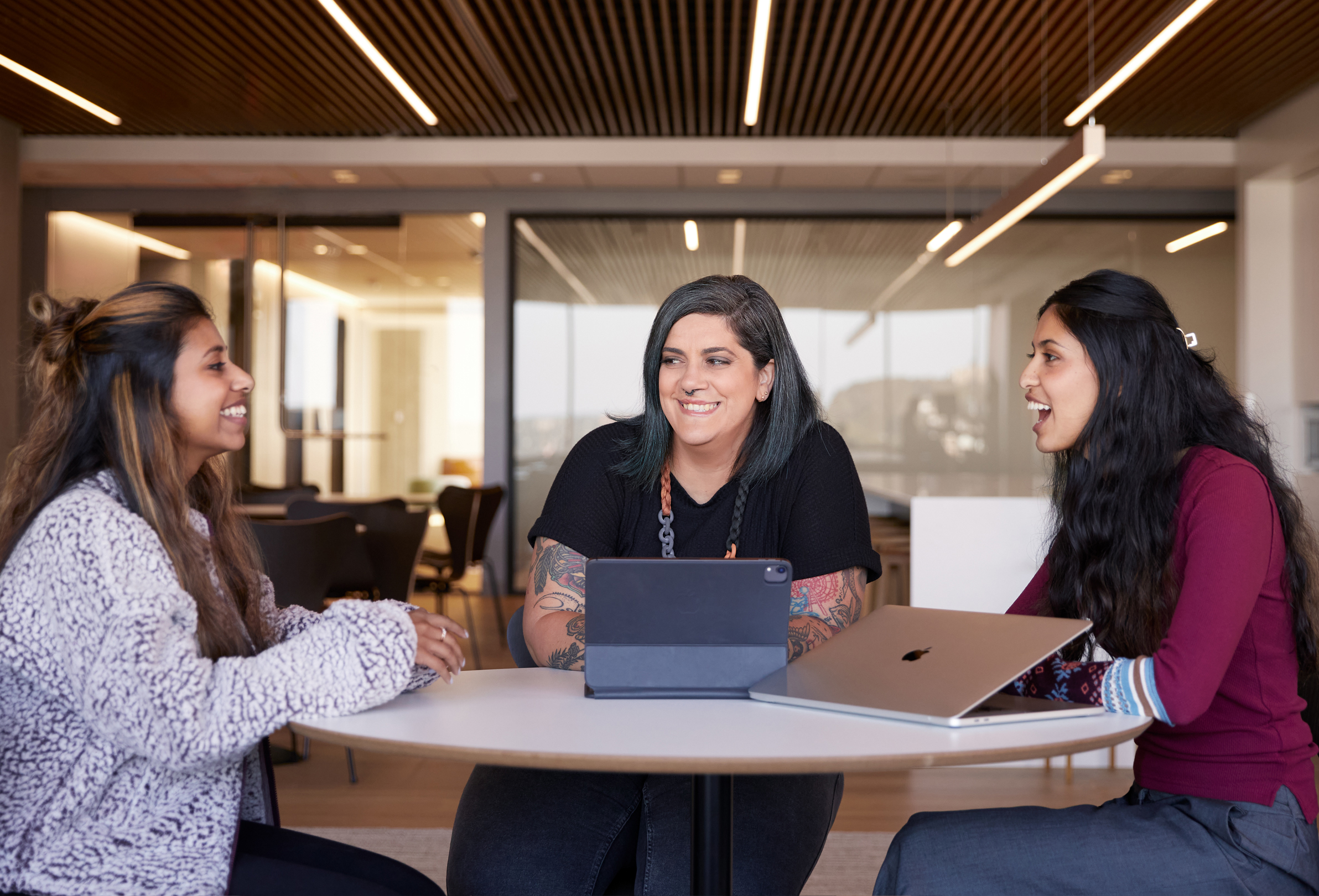 Tre persone del team Apple che parlano sedute a un tavolo.