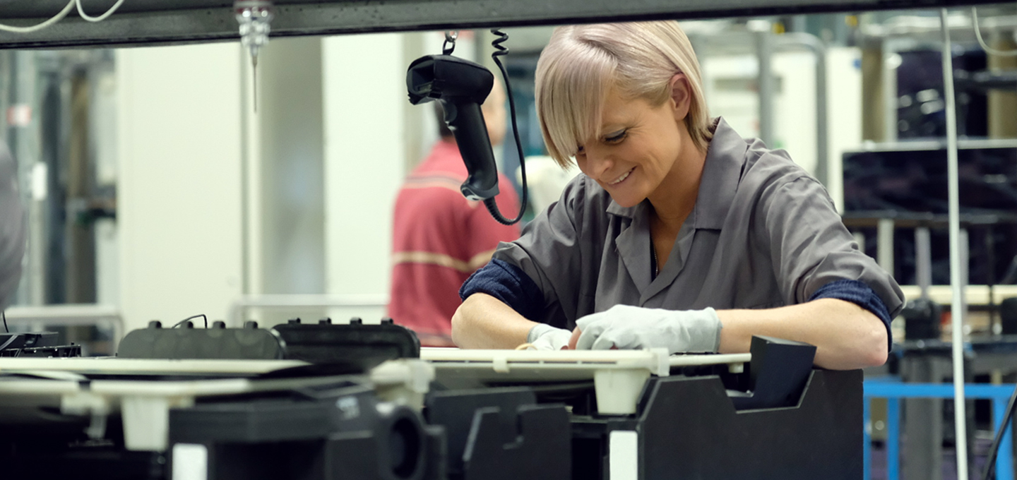 Due dipendenti ispezionano il case esterno del MacBook sulle griglie di anodizzazione al titanio presso uno stabilimento Apple