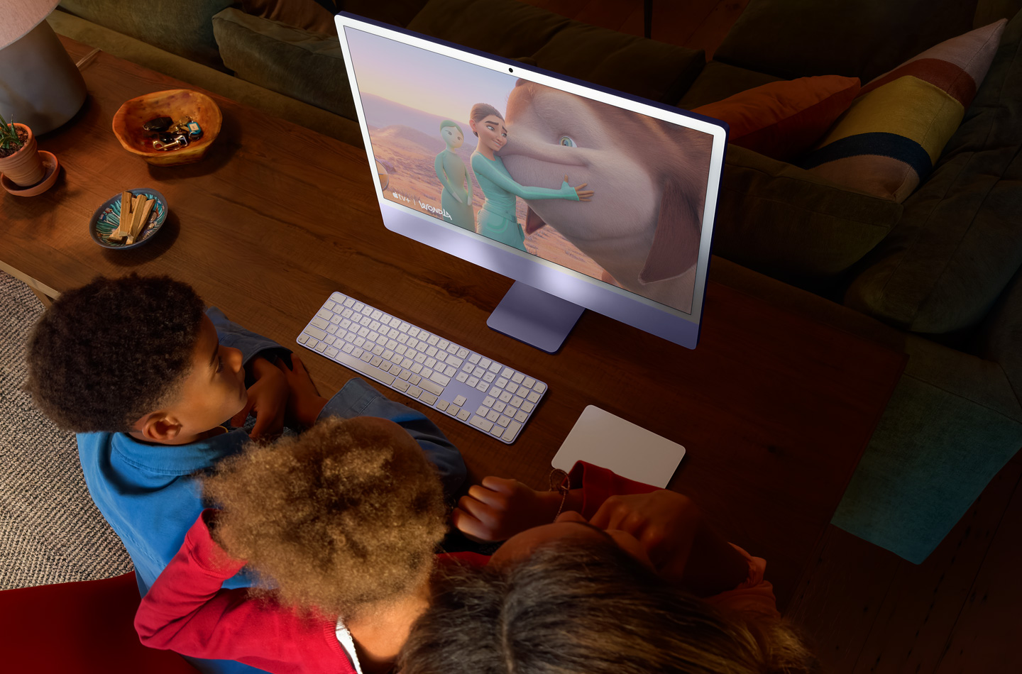 Tres niños ven los dibujos de WondLa en un iMac