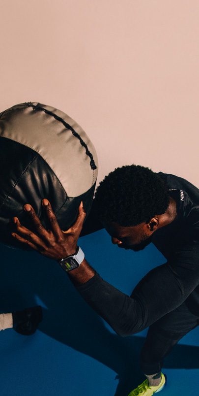 A man wearing an Apple Watch Series 10 holds a medicine ball during a workout.